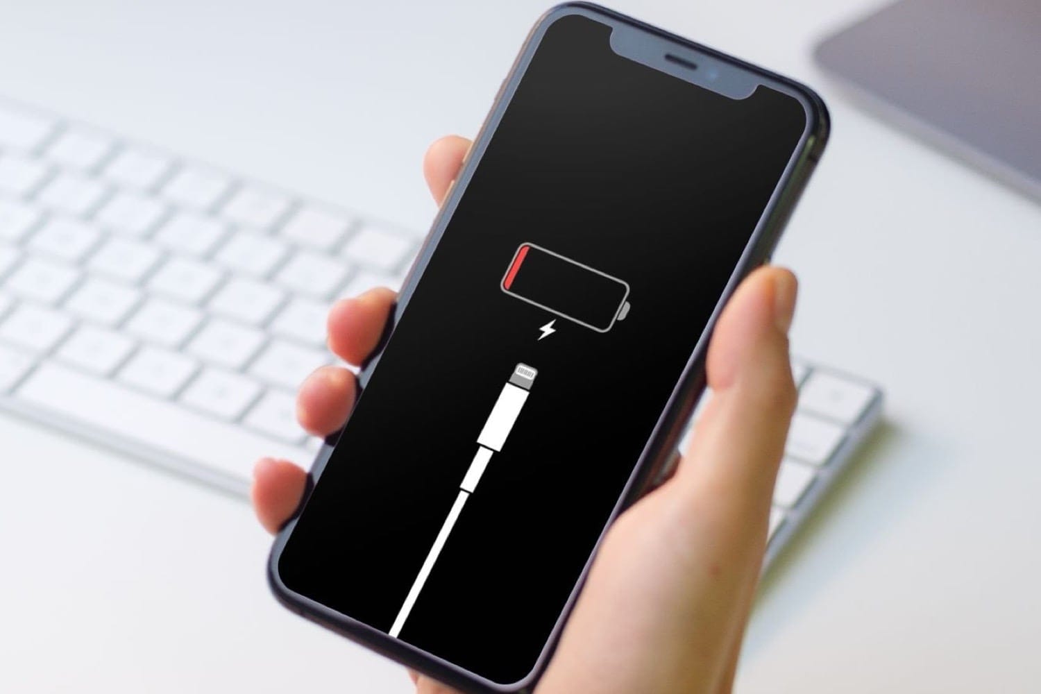Un iPhone affichant plus de batterie, fond noir avec l'icône de la batterie en attente du rechargement. Améliorer l'autonomie de votre iPhone.